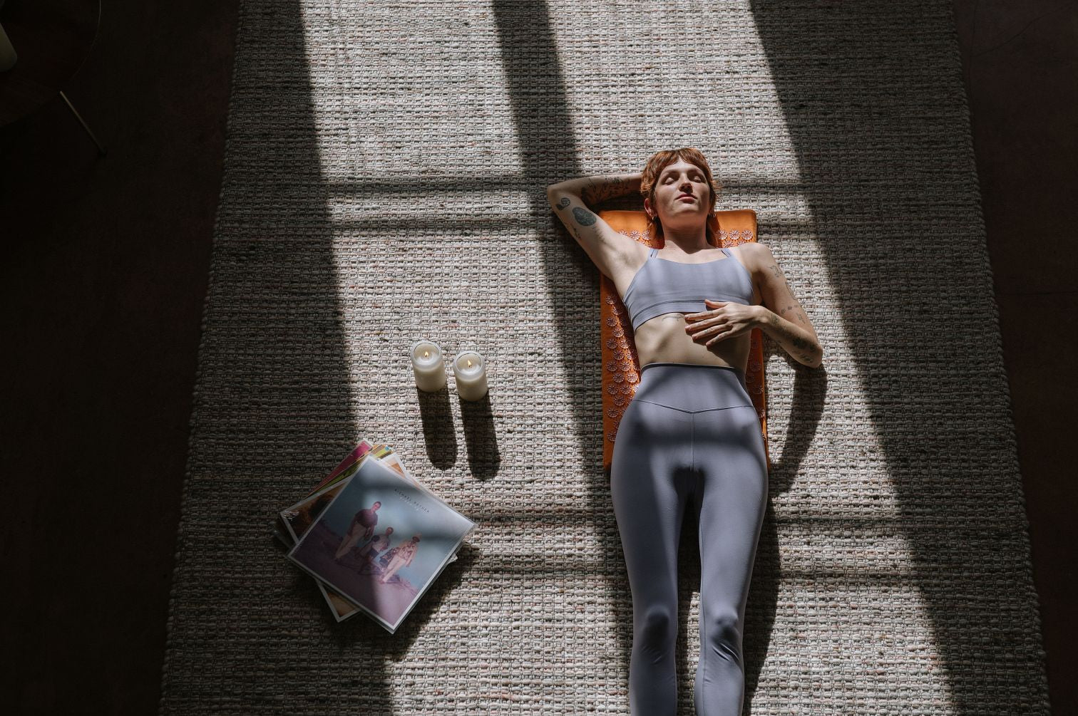 Woman laying on a Shakti Acupressure Mat on beige carpet