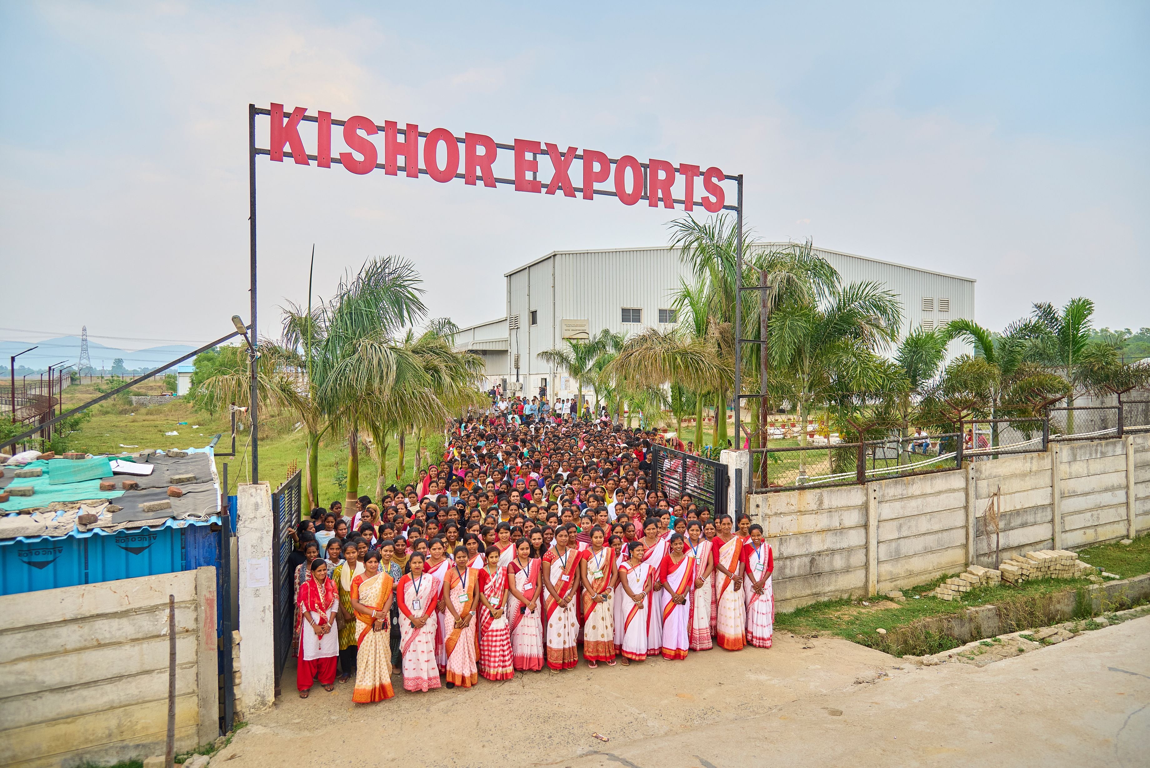 Group of people in front of a building with 'Kishor Exports' sign