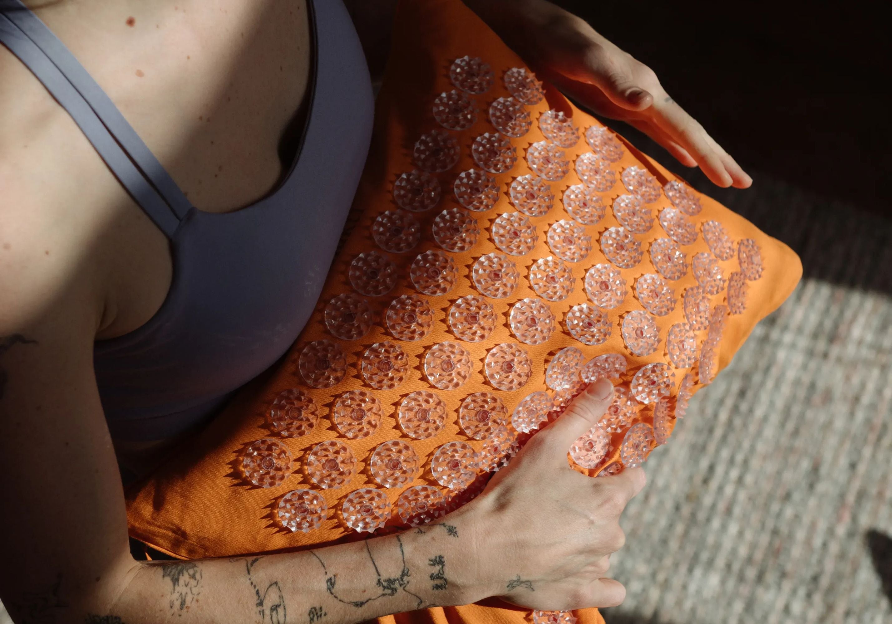 Person shaping a Shakti Premium Acupressure Pillow in Orange in their hands.