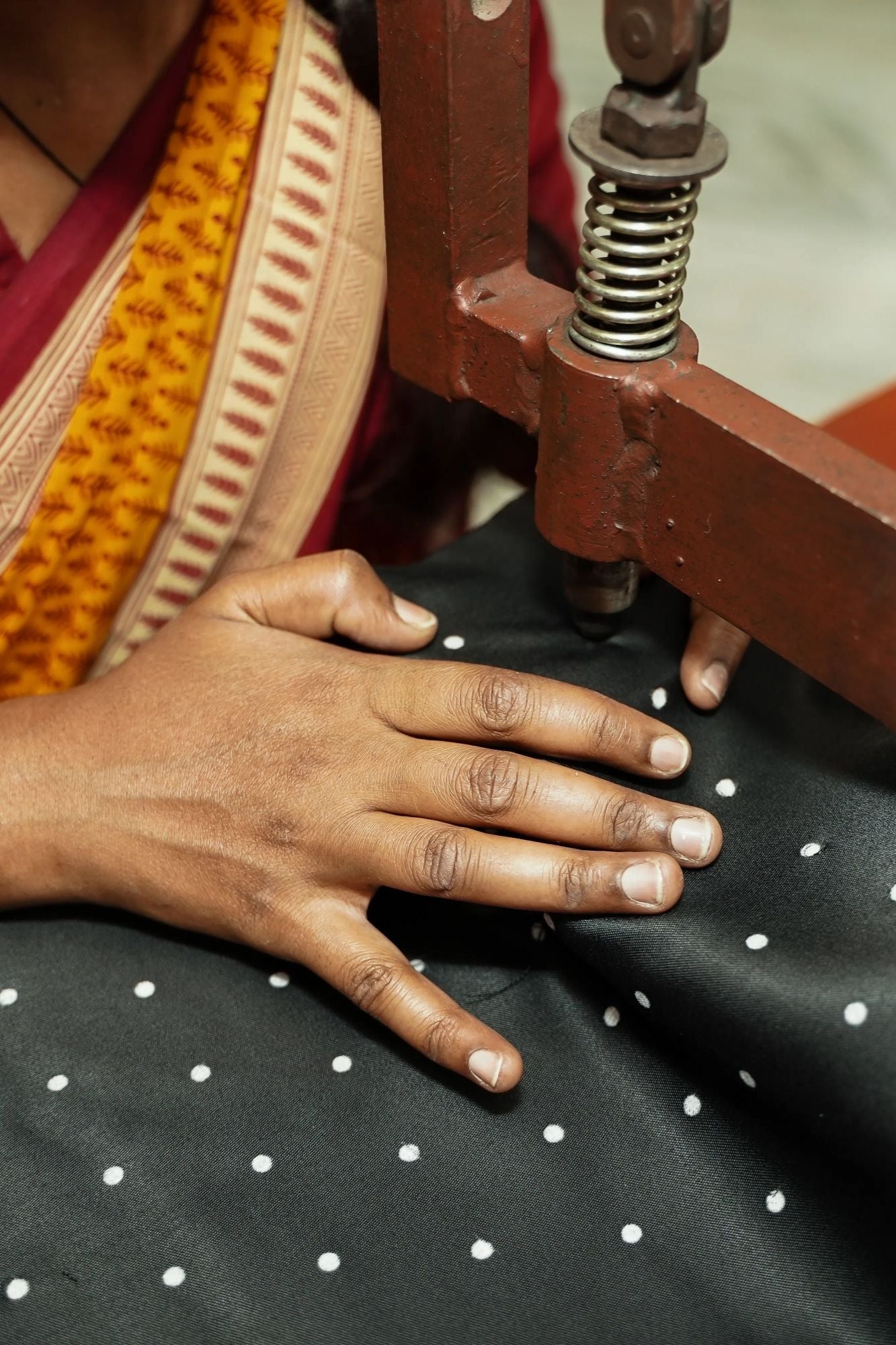 Person working with fabric and a sewing machine, focusing on hands and material.
