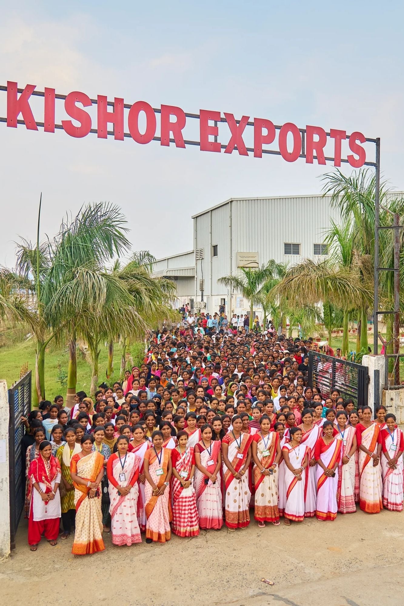 Large group of people in front of a building with 'Kishor Exports' sign.